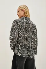 Camisa de algodón con estampado tipo paisley en tonos blanco, negro y azul. Presenta cuello clásico, cierre frontal con botones y mangas largas con puños abotonados.