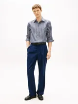 Camisa Tommy Hilfiger de corte regular, confeccionada en popelín de algodón azul con rayas verticales texturizadas. Presenta cuello camisero, cierre frontal de botones, mangas largas con puños abotonados y logo bordado en el pecho.