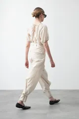 Pantalón baggy negro de silueta relajada con volumen amplio y caída fluida. Presenta detalles de ajuste con hebillas metálicas en el bajo y un cinturón de tela con hebilla metálica en la cintura.