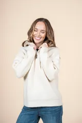 Cardigan de punto color crema, con cuello alto y cierre frontal parcial, de manga larga y diseño holgado.