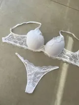 Conjunto de lencería compuesto por un corpiño taza soft con detalles de encaje y una bombacha tipo less regulable a juego, ambos en color blanco.
