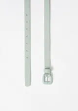 Cinturón fino color beige con hebilla metálica cuadrada.