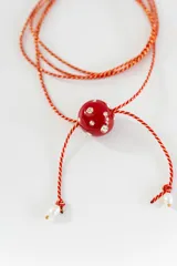 Gargantilla tipo bolo tie de tiento trenzado verde con dije esférico celeste con brillos incrustados.