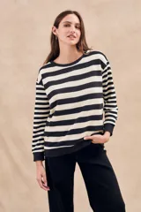 Sweater de punto a rayas horizontales anchas en color negro y crudo, de corte oversize, mangas largas y cuello redondo.