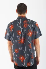 Camisa de manga corta con estampado de palmeras en tonos naranja y blanco sobre fondo gris.