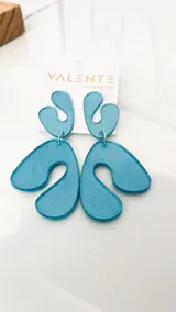 Par de aros colgantes de acrílico celeste con formas abstractas.