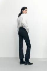 Pantalón negro de corte recto, con cintura alta, bolsillos laterales y cierre frontal con botón y cremallera.