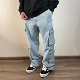 Pantalón jean celeste claro, corte holgado con bolsillos cargo laterales.