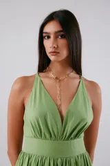 Vestido midi de color verde, con escote en V profundo, banda ancha bajo el busto y falda amplia con gran volumen. Presenta espalda baja y cierre invisible.