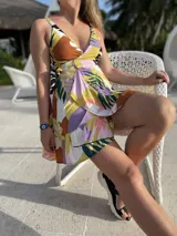 Vestido corto de fibrana con estampado abstracto en tonos amarillo, marrón, lila, verde y negro. Diseño cruzado con lazo en la cintura y breteles finos.