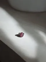 Anillo de acero quirúrgico con diseño de piedra ovalada en tono rosado con textura craquelada.