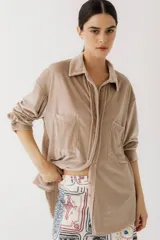Camisa beige de terciopelo con cuello clásico, cierre frontal con botones, dos bolsillos de parche en el pecho y mangas largas con puños abotonados.