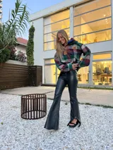 Pantalón de cuero de tiro alto con corte oxford, presenta un tajo en el ruedo lateral y un botón metálico distintivo.