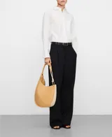 Bolso de hombro Adolfo Dominguez modelo Cumbre II, de diseño redondeado tipo media luna. Confeccionado en tejido con recubrimiento de poliuretano de textura granulada en color tostado, con detalles en blanco y asa corta tubular ajustable con pieza metálica. Incluye un compartimento principal con cierre de cremallera y bolsillo interior. Logo grabado en la parte frontal.
