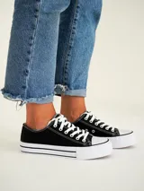 Zapatillas urbanas negras con plataforma blanca y cordones blancos.