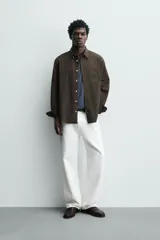 Camisa de corte regular fit confeccionada en tejido de algodón con diseño de rayas verticales. Presenta cuello abotonado, manga larga con puños abotonados, bolsillo plastrón en el pecho y cierre frontal con botones.