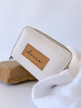 Billetera pequeña de cuero color crudo, con cierre metálico y monedero interno.