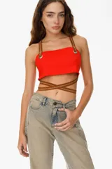 Top rojo ajustable con tiras de cuero sintético marrón en el contorno del pecho y en los breteles. Cuenta con dos ojales metálicos y tiras largas que permiten entrecruzarse en el torso.