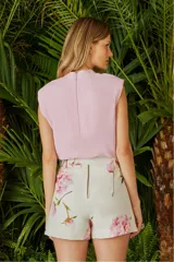 Blusa color rosa pálido sin mangas, con cuello alto y lazo decorativo.