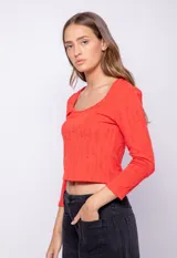 Top rojo de manga larga y cuello redondo con textura sutil en relieve, corte ajustado.