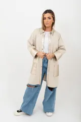 Camisa larga color beige de tejido de punto en algodón, con cuello camisero, cierre frontal con botones a presión y detalles en cuero color dorado en cuello, solapa, puños y bolsillos frontales.