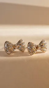 Par de caravanas doradas con forma de moño cubiertas de strass.