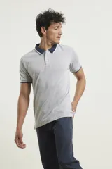 Chomba de piqué azul con cuello clásico, mangas cortas y corte recto. El cuello y los puños tienen detalles a contratono en azul marino y blanco.