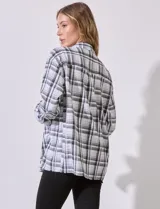 Sobrecamisa cuadrillé blanca y negra con cuello con solapa, abertura central con botones, bolsillos aplicados y mangas largas regulables con presilla y botón. Terminación de ruedo desflecado.