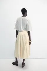 Falda midi de tiro medio ZARA Woman Collection confeccionada en hilatura con lino, con detalle de pliegues, bajo acabado en línea evasé y cierre lateral con cremallera oculta en costura.