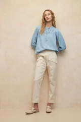 Pantalón color beige de algodón, tipo paper touch, con elástico en la cintura y cordones. Tiene un fit recto con bolsillos de solapa y botones a tono.