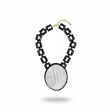 Collar de cadena de eslabones gruesos de resina negra con un gran medallón central ovalado de nácar enmarcado en resina negra. Incluye cierre de mosquetón y cadena de alargue metálica.