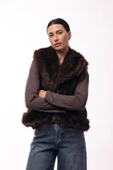 Chaleco acolchado color marrón con terminaciones de piel sintética en los bordes y cuello, aportando volumen y textura.