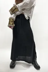 Falda larga tejida en color negro, con diseño de punto abierto y cintura ajustable mediante cordón.