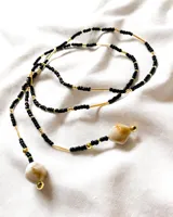 Gargantilla tipo choker con cuentas negras y doradas, tubos dorados y dijes colgantes de piedra natural color crema.