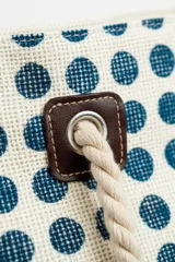 Bolso de playa o tote bag con diseño de patchwork en tonos rosados, naranjas y blancos. Presenta secciones con estampado de lunares rojos y secciones con tejido de rafia. Las asas son de cuerda trenzada.