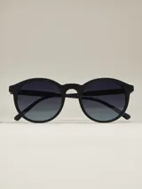 Anteojos de sol con armazón negro mate y forma redonda. Lentes con filtro degradado oscuro.