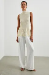 Musculosa color crema tejida a crochet, con cuello alto y flecos en el ruedo.