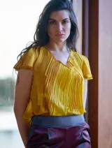 Pantalón de satén pintado a mano con diseño abstracto en tonos verde azulado y ocre.