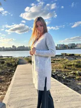 Saco de punto gris melange abierto, largo hasta la rodilla, con mangas largas y bolsillos frontales aplicados.
