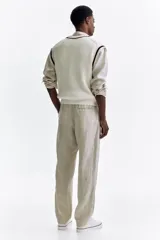 Pantalón de lino liviano para hombre, de corte regular fit y color beige. Presenta cintura elástica con cordón de ajuste oculto, bolsillos laterales discretos y un bolsillo trasero insertado.