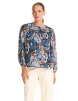 Blusa de gasa con estampado floral en tonos azules y marrones, con sutiles hilos de lurex dorados. Presenta cuello a la base, abertura central con botones, canesú delantero con pasamanería calada y mangas largas con puños elastizados. Incluye forro interno a tono.