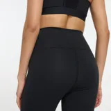 Calza deportiva New Balance negra, de tiro alto, con logo reflectivo en la pierna izquierda y tecnología NB DRY.