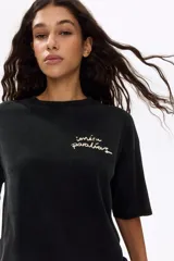 Remera oversized de algodón color negro, con cuello redondo acanalado, mangas cortas y diseño estampado en el pecho.