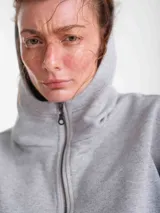 Campera negra de tela deportiva fina con capucha, cierre frontal completo, diseño estilo corset en la cintura y mangas largas con puños tipo guante con abertura para el pulgar.
