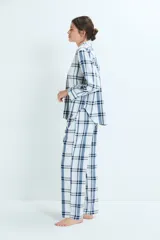 Pijama de dos piezas con estampado de cuadros en tonos azules y blancos. La parte superior es una camisa de manga larga con cuello camisero y cierre frontal de botones. La parte inferior es un pantalón de corte recto con cintura elástica.