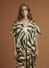 Chaqueta tipo kimono con estampado animal print de cebra en tonos marrón y negro. Tiene mangas 3/4 con bolsillos de parche y está confeccionada en lino.