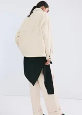 Chaqueta de algodón estilo denim, de diseño oversize, color beige, con cuello alto, manga larga, bolsillos de parche con solapa y cierre frontal de botones oscuros.