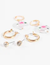 Set de aros plateados con tres pares diferentes: aros colgantes con dije ovalado con diseño de flor rosa, aros tipo argolla y aros tipo botón con strass.