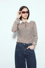 Remera de manga larga con diseño de rayas verticales en color marrón y blanco. Presenta cuello polo con cierre de botones frontal y un corte ajustado al cuerpo.