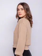 Cárdigan corto color beige, de manga larga y escote en V. Tiene cuatro botones brillantes.